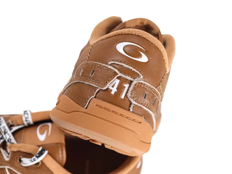 Brown leather shoe with white stitching and reinforced heel design, visible logo.