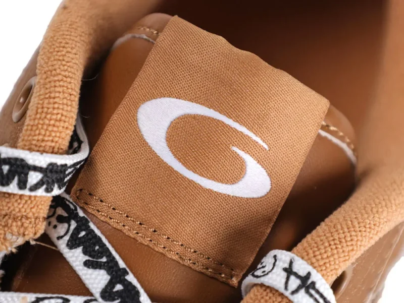 Brown fabric shoe tongue with white logo, surrounded by patterned shoelaces.