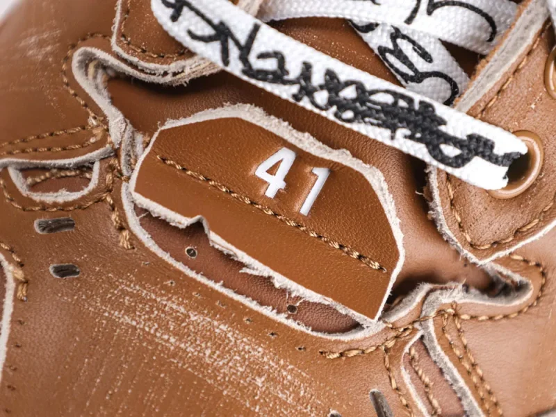Brown leather shoe with stitched number 41 and black-and-white patterned laces.
