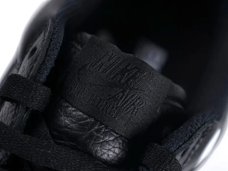 Close-up of black leather shoe tongue with textured fabric label and laces.