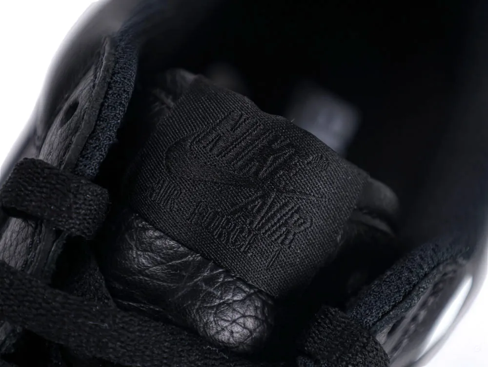 Close-up of black leather shoe tongue with textured fabric label and laces.