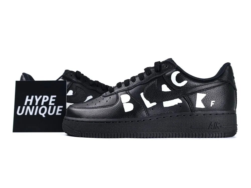 Black leather sneakers with textured surface and white letter accents on the side.