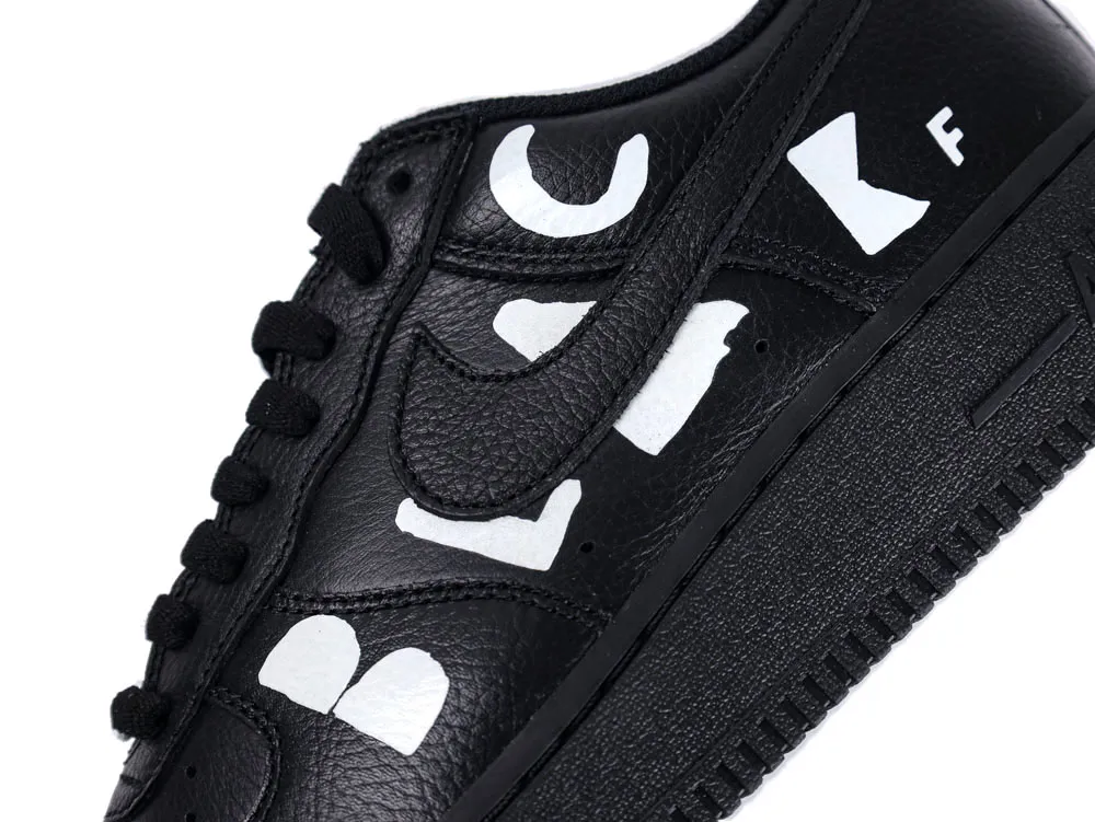 Black leather sneaker with bold white letters and black laces, close-up view.