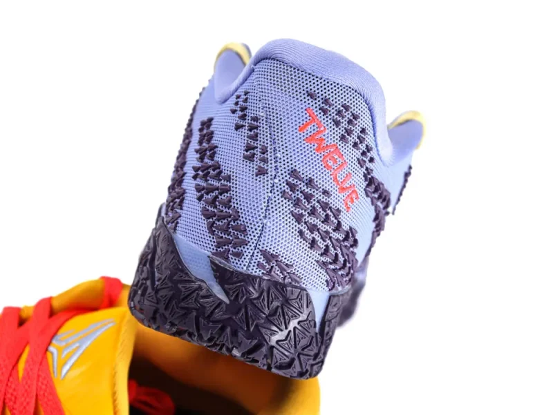 Close-up of a purple mesh sneaker heel with textured black sole and red text.