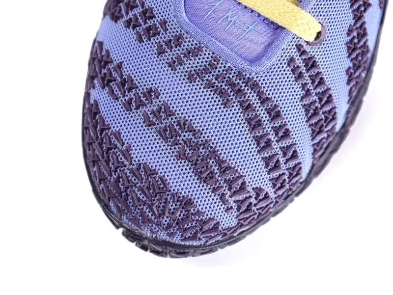Close-up of a purple mesh sneaker with textured patterns and a yellow lace.
