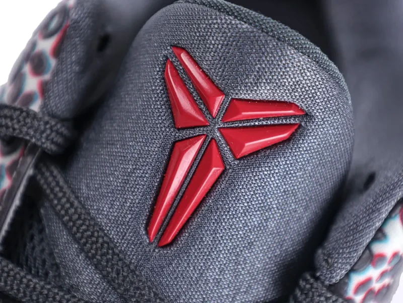 Gray fabric shoe tongue with a red plastic emblem and black laces.
