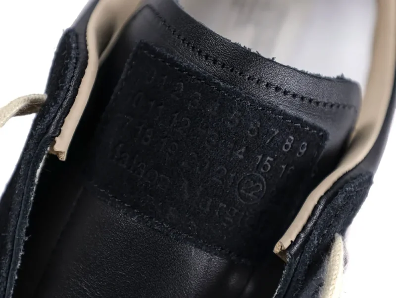 Close-up of black leather shoe tongue with stitching and numbering details.