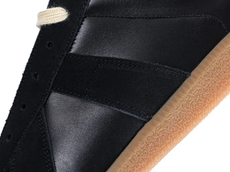 Black leather and suede sneaker upper with beige rubber sole detail.
