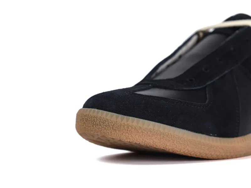 Black suede shoe with a rubber sole, close-up of the toe section.