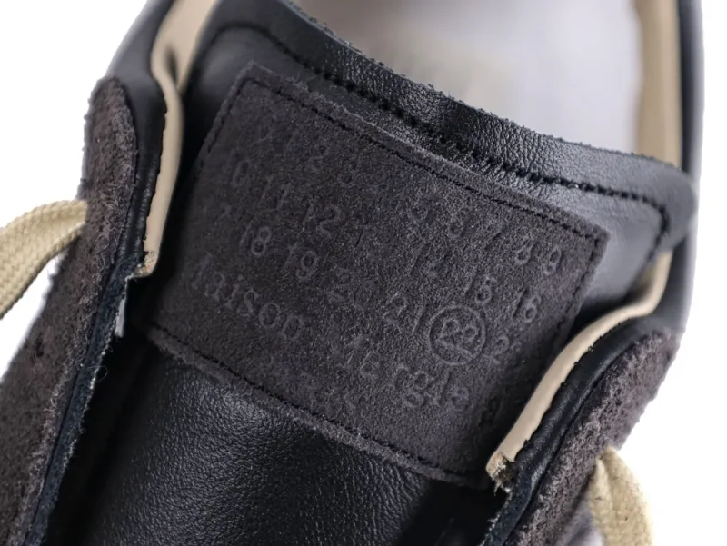 Close-up of a black leather shoe tongue with embossed numbers and beige laces.