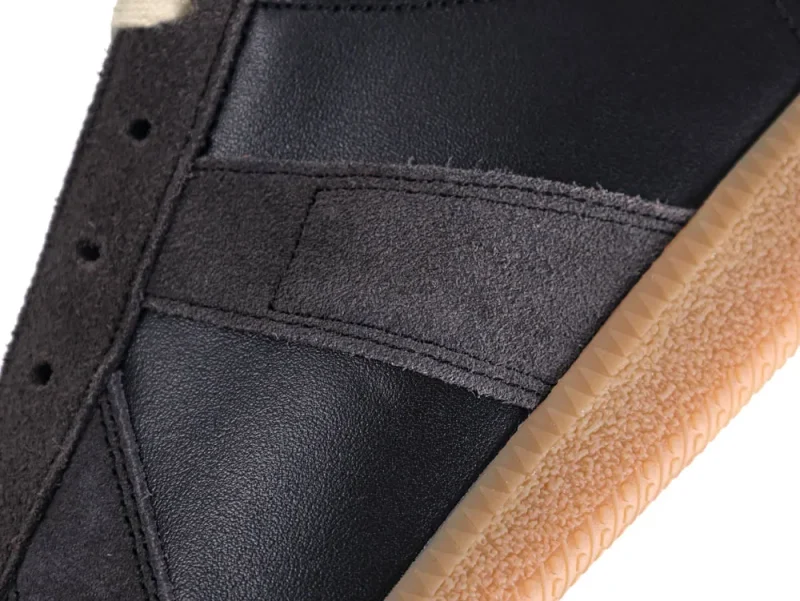 Close-up of shoe featuring black leather and suede with a beige rubber sole.
