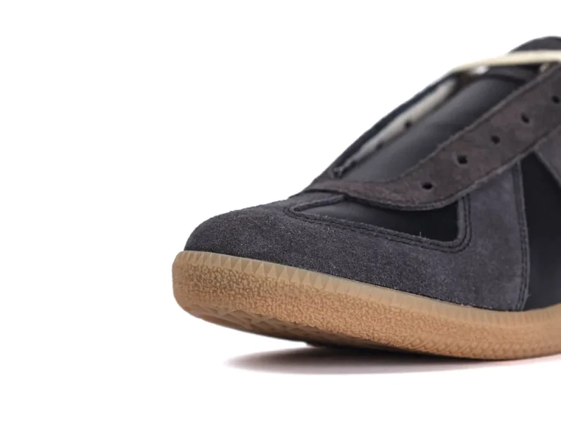Close-up of black suede shoe toe with brown textured rubber sole.