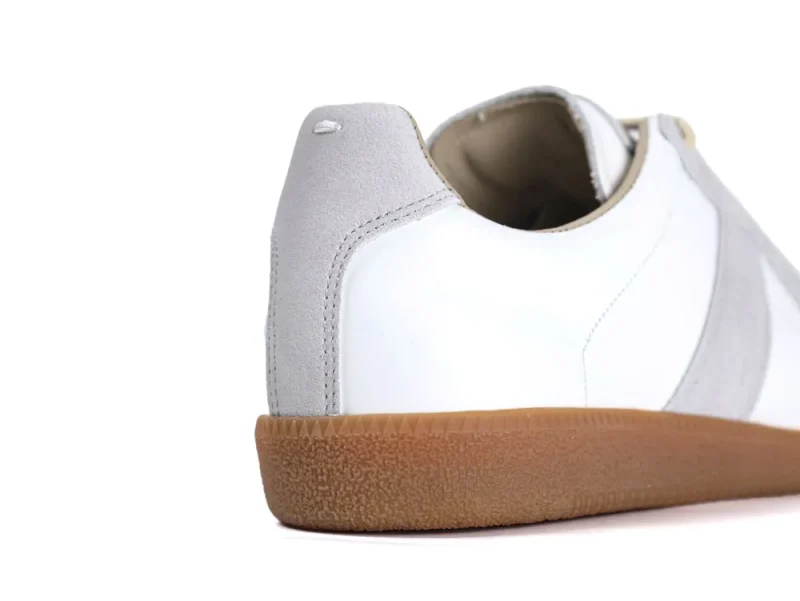 White leather shoe with a gray suede accent and brown rubber sole.