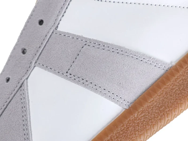 Close-up of a white and gray suede sneaker with brown rubber sole.