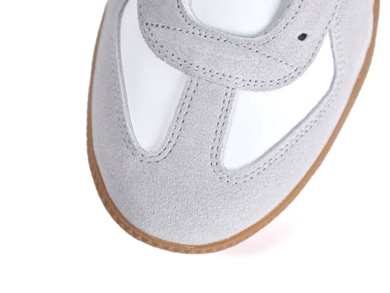 Gray suede shoe with brown sole and white insole, showing stitched upper part.