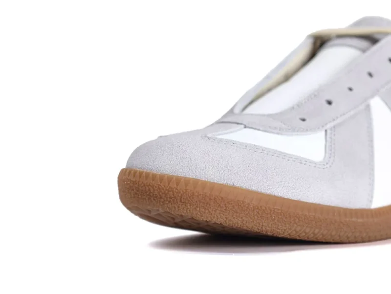 Close-up of gray suede sneaker with a white panel and gum rubber sole.