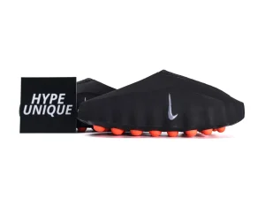 Black fabric sneakers with bright orange soles and silver logo. Displayed with branding.