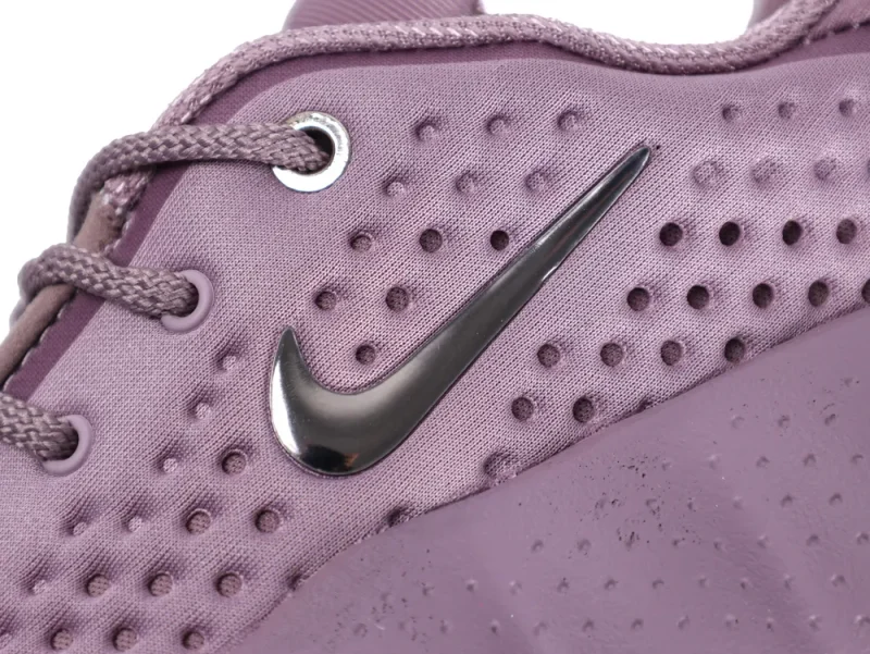 Purple fabric sneaker with textured surface and metallic logo detail on the side.