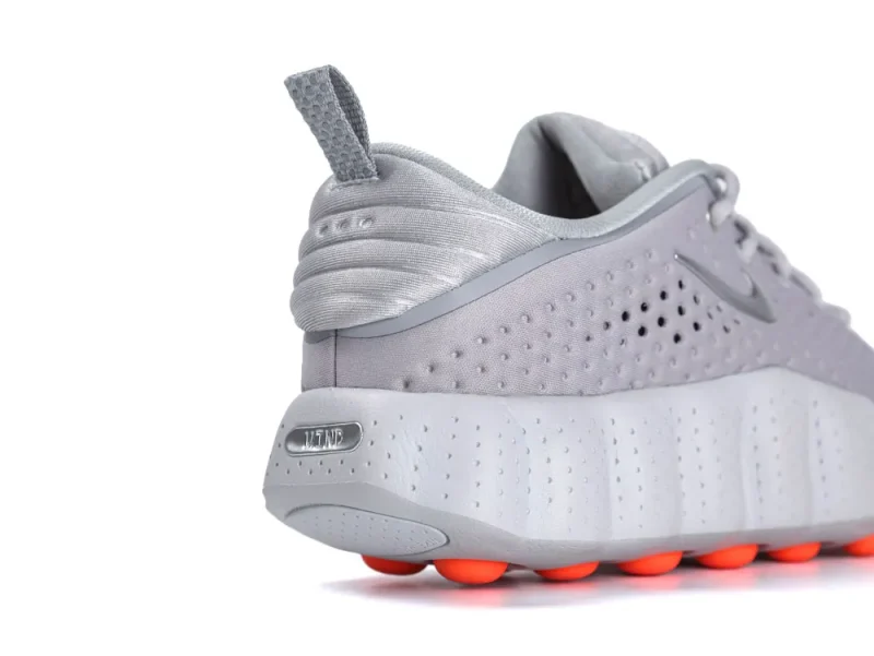 Gray sneaker with perforated synthetic material and orange rubber soles.