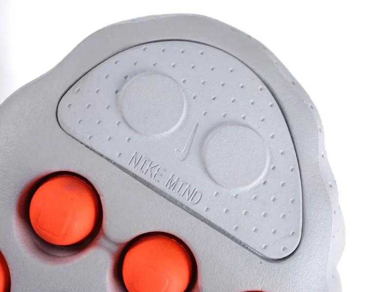 Gray rubber shoe sole with orange accents, featuring circular textured design and branding.