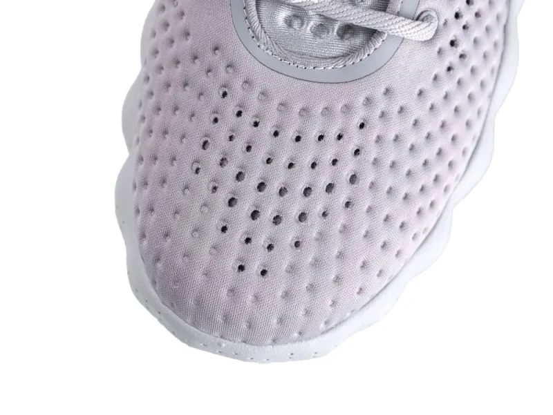 Close-up of gray fabric shoe toe with perforated design and white lace.