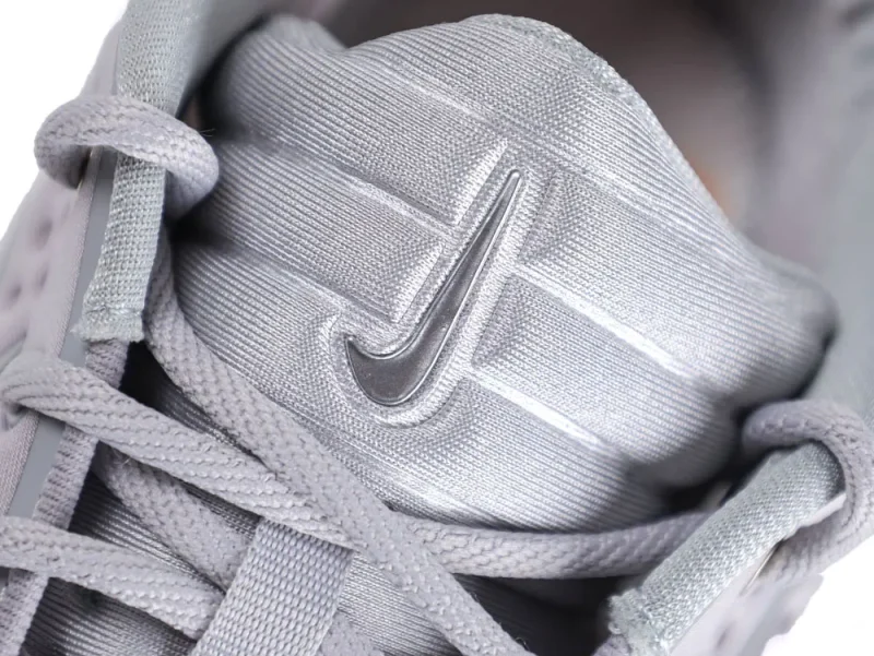 Close-up of silver fabric shoe tongue with laces and logo detail.