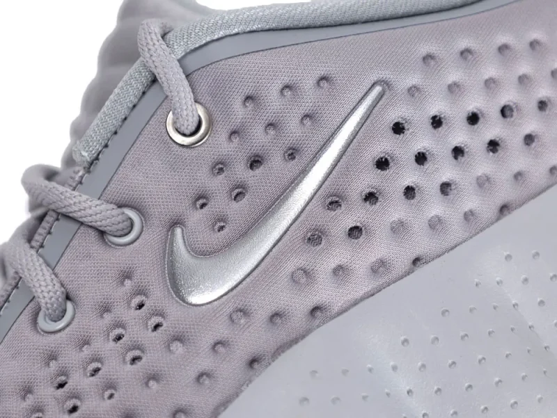 Gray fabric sneaker with perforated texture and metallic silver logo detail.