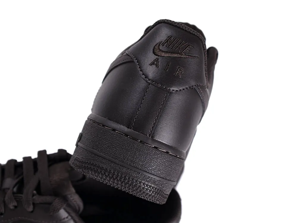 Black leather sneaker with embossed branding on the heel.