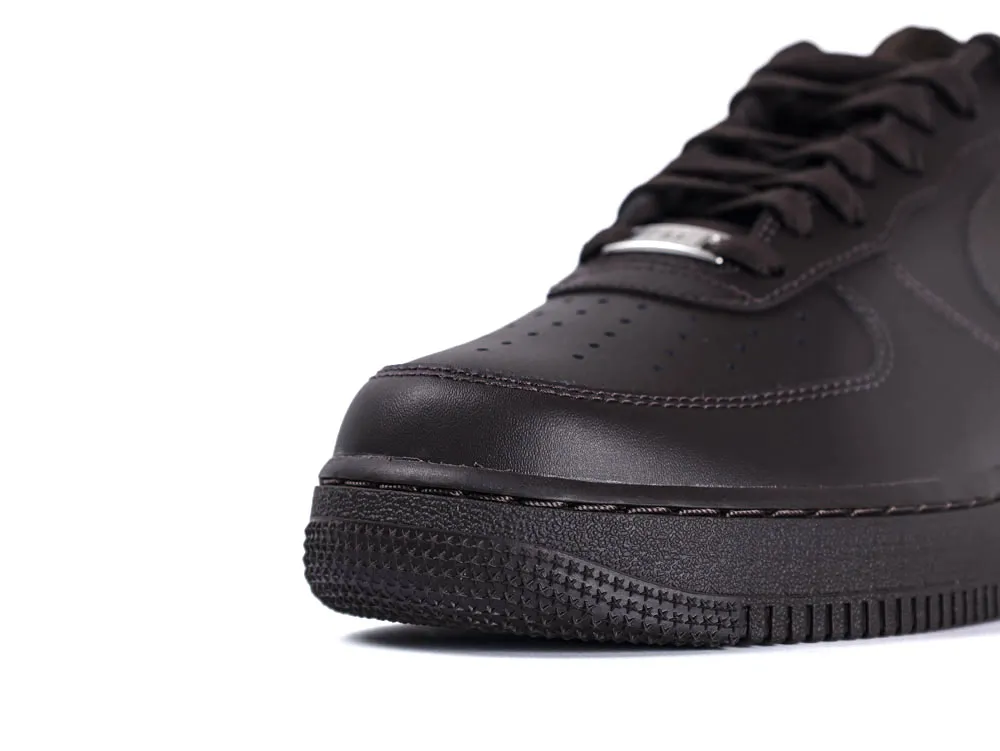 Close-up of a black leather sneaker showing the textured sole and perforated design.
