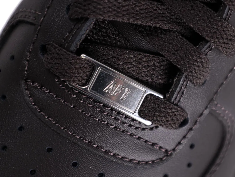 Close-up of a black leather shoe with black laces and metal AF1 tag.