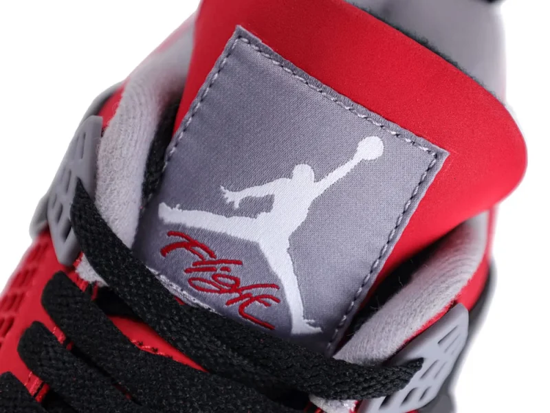 Close-up of sneaker tongue featuring red, gray, and black fabric with stitching details.