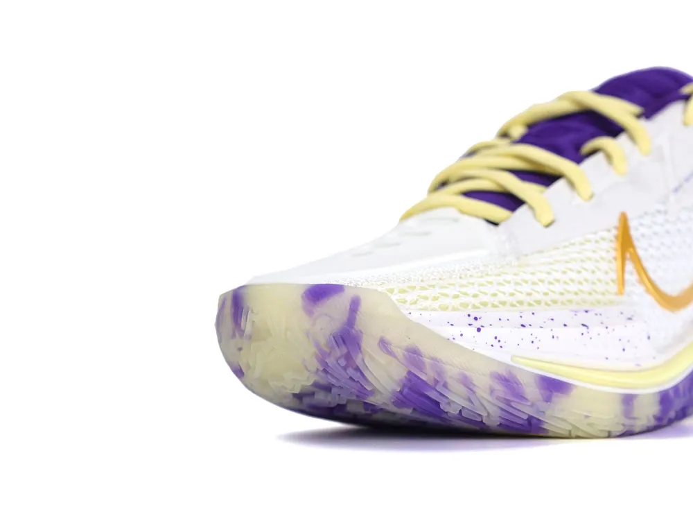 Close-up of a white sneaker with purple and yellow accents and textured material.
