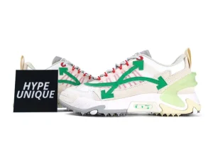 White and beige sneakers with green arrow design and red lace accents.