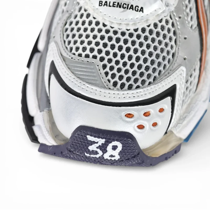 Close-up of silver mesh sneaker with textured sole and orange accents, size marked 38.
