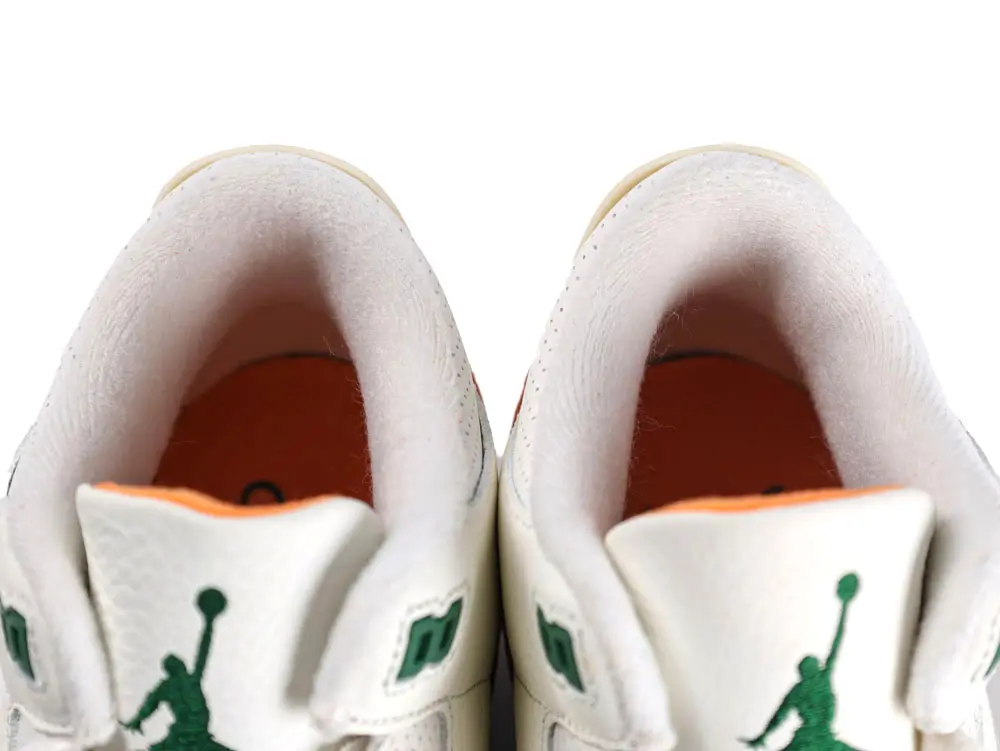 White leather sneaker interior with green logo and orange lining details.
