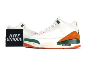 White leather sneakers with green and orange suede accents, featuring perforated detailing.
