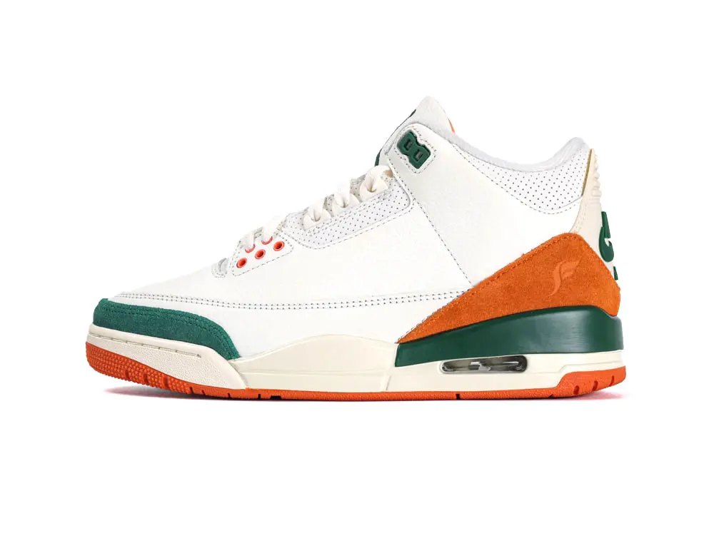 White leather sneaker with orange suede accents and green rubber details.