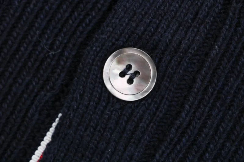 Close-up of button detail on navy knit cardigan.