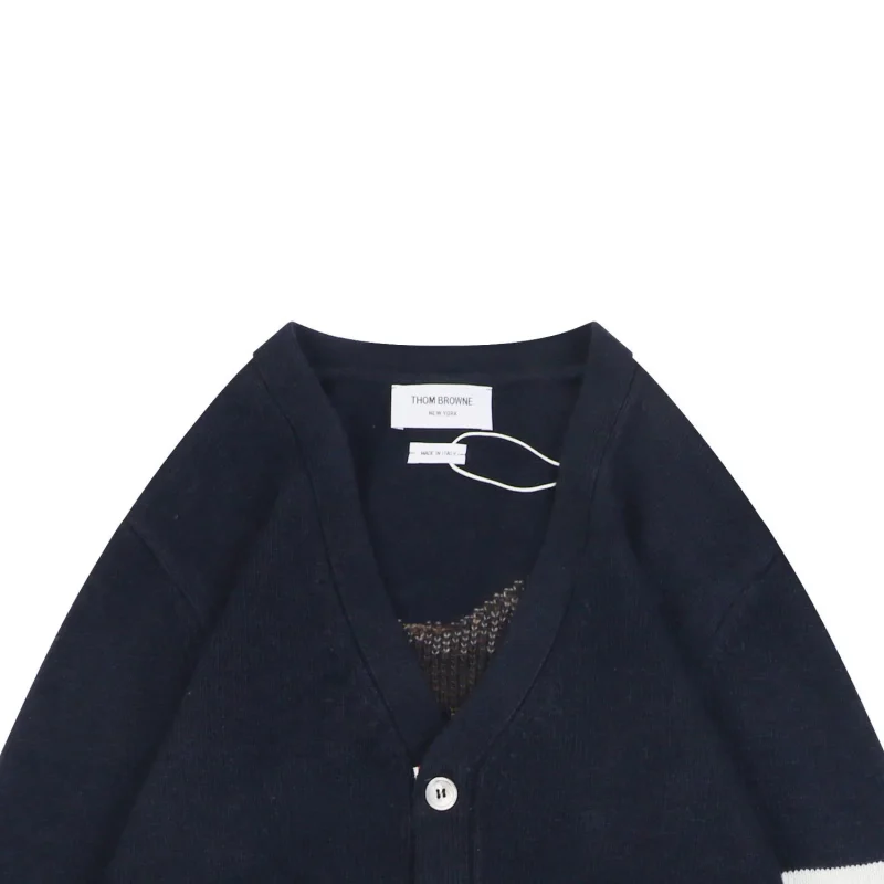 Close-up of navy knit cardigan neckline and brand label detail.