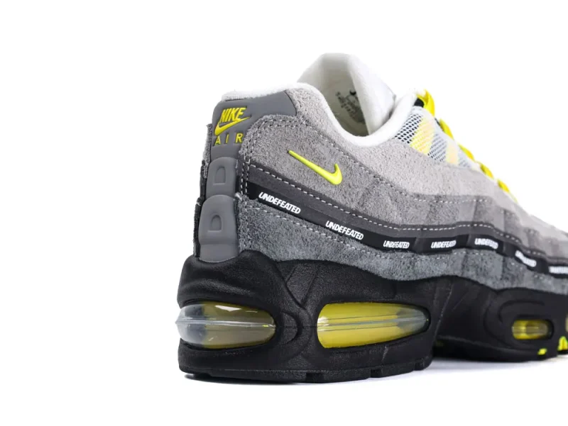 Gray suede sneaker with yellow accents, featuring a visible air cushion sole.