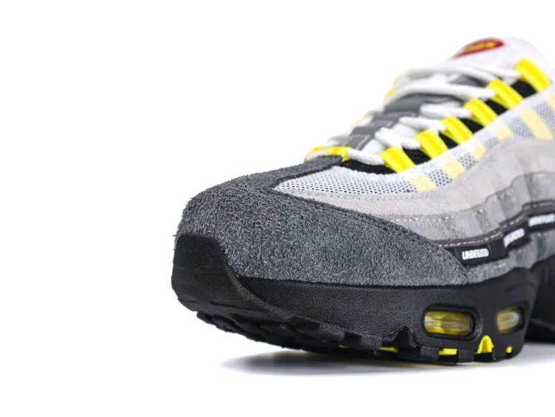 Gray suede sneaker with yellow accents and mesh details on the upper.