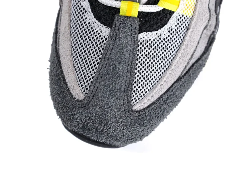 Close-up of a gray suede and mesh sneaker toe with yellow accents.