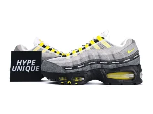 Gray suede sneakers with yellow accents, black sole, mesh material, and branded details.