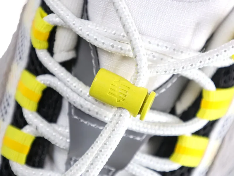 Close-up of sneaker laces with yellow plastic lace lock detail.
