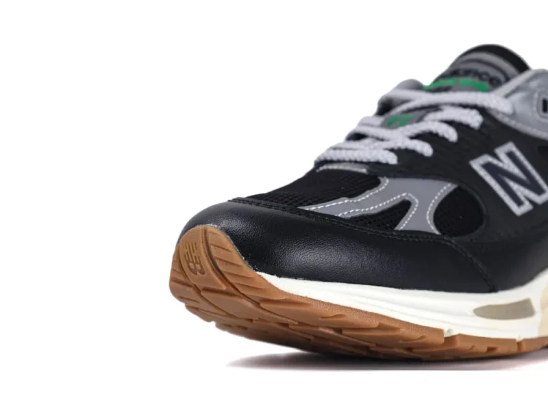 Black and gray sneaker with leather upper and brown rubber sole detail.