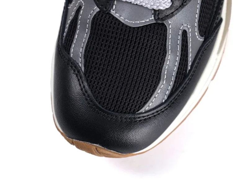 Close-up of a black leather sneaker toe with mesh and gray accents.