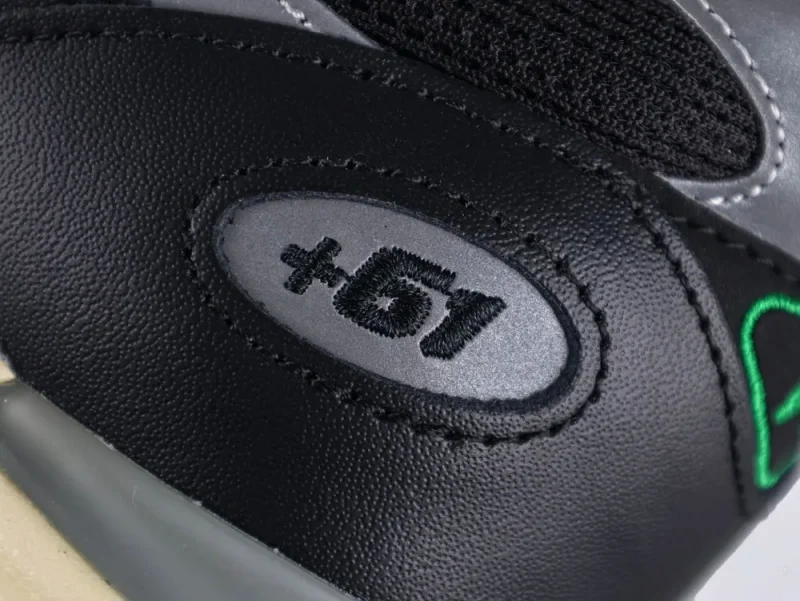 Close-up of black leather shoe with embroidered logo on the heel.