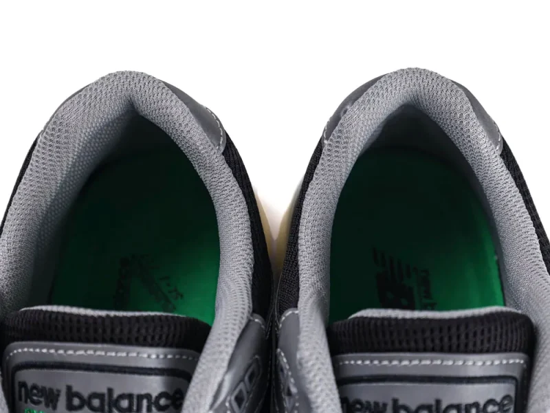 Gray mesh sneaker interior with green insoles, featuring New Balance branding.