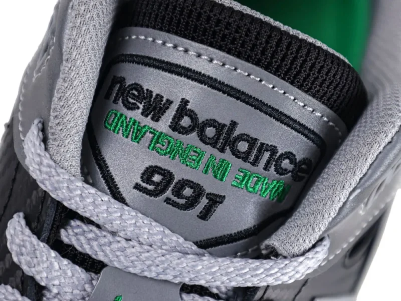 Gray sneaker tongue with embroidered branding, featuring light gray laces and stitching.