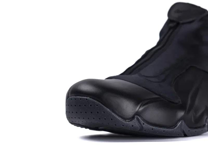 Close-up of a black leather shoe, focusing on the toe area with perforations.